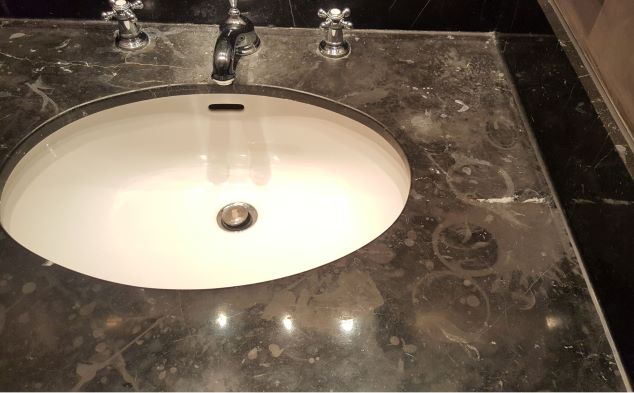 A vanity top in a London hotel etched by various products ranging from aftershave, perfume and the use of the wrong type of cleaning products.